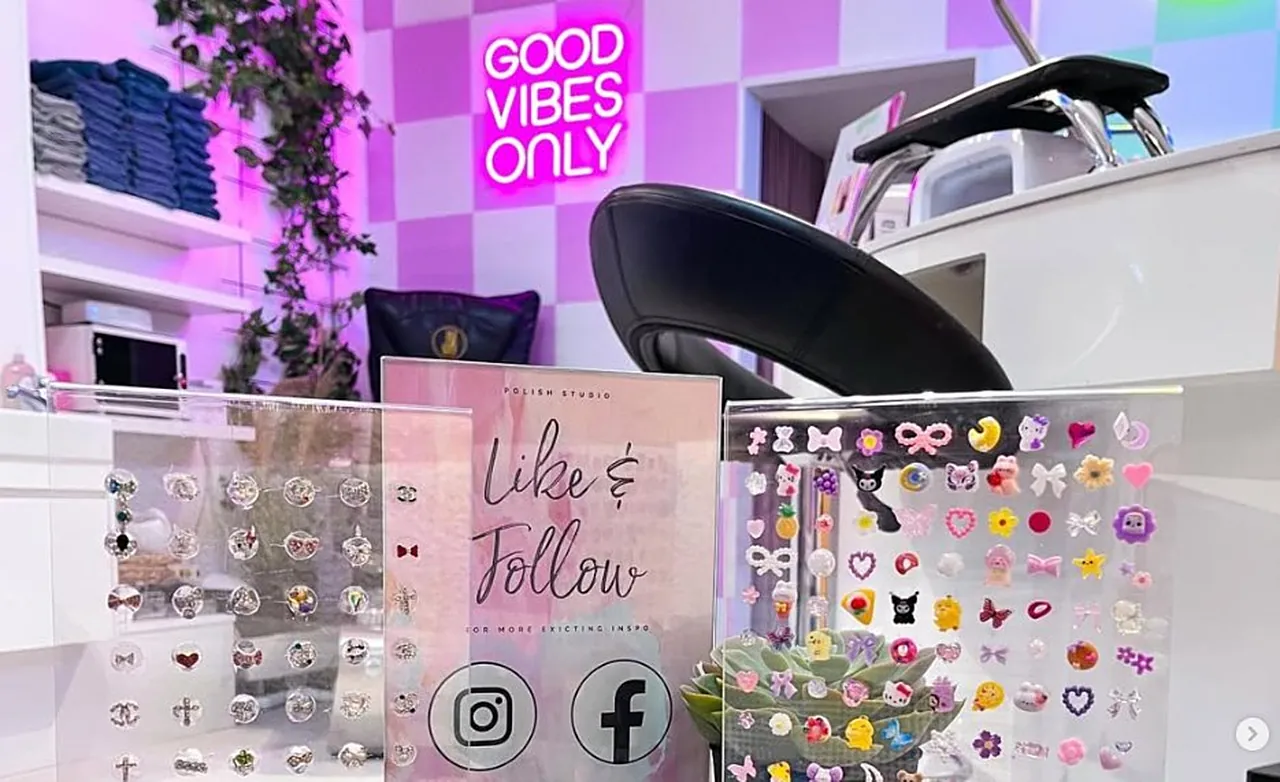 Polish Nailbars studio med rosa rutig vägg, neonskylten Good Vibes Only och en bricka med charms och färgprover.