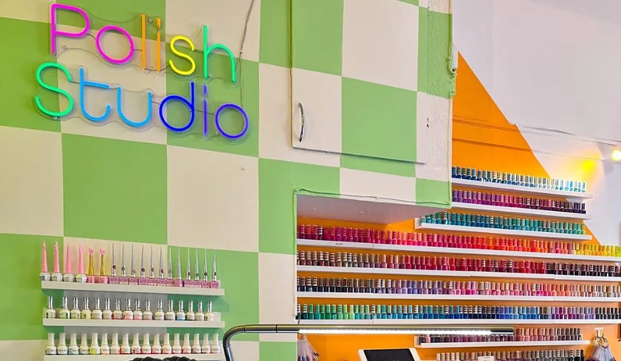 Polish Nailbars studio med grön rutig vägg, neonskylten Polish Studio och en regnbågssorterad nagellacksvägg.
